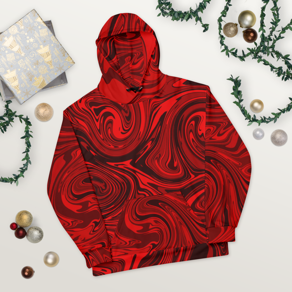 A black and red abstract swirl patterned hoodie laid flat on a light wooden surface. The design features bold, fluid lines that create a vibrant, modern look. The hoodie's front pocket and hood are visible, showing the seamless all-over print. Festive ornaments, greenery, and wrapped gifts are arranged around it for a decorative, holiday-inspired presentation.